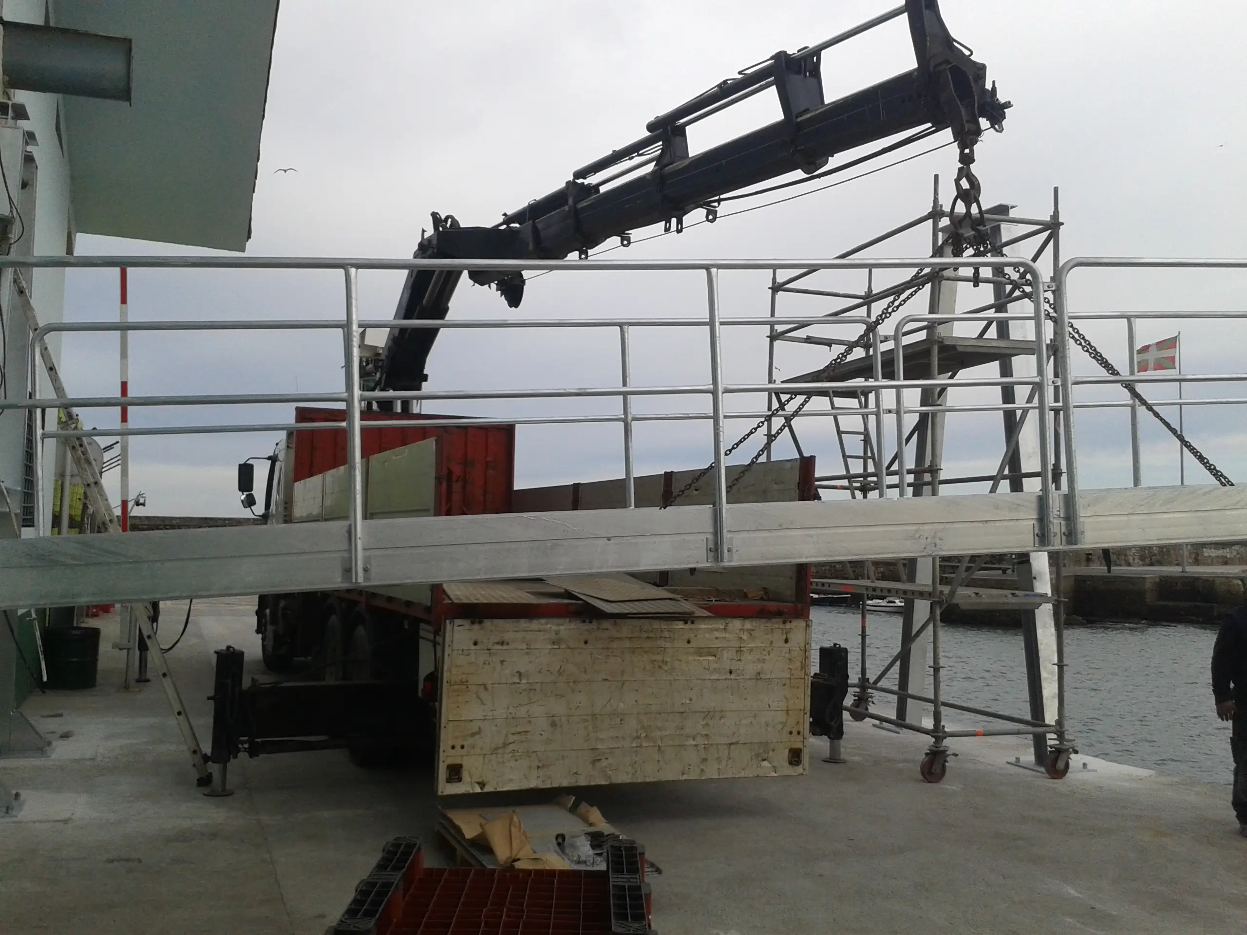 Grúa instalando pasarela para un sinfín transportador de hielo hasta un barco pesquero en el País Vasco